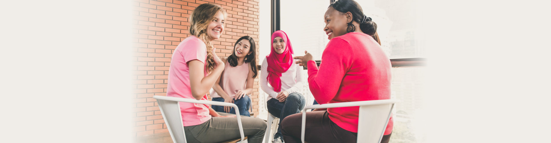 Multiethinic women wearing pink color clothes sitting in circle talking and meeting