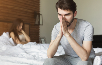 Bed problems. Depressed men sitting on the edge of bed in bedroom after quarrel